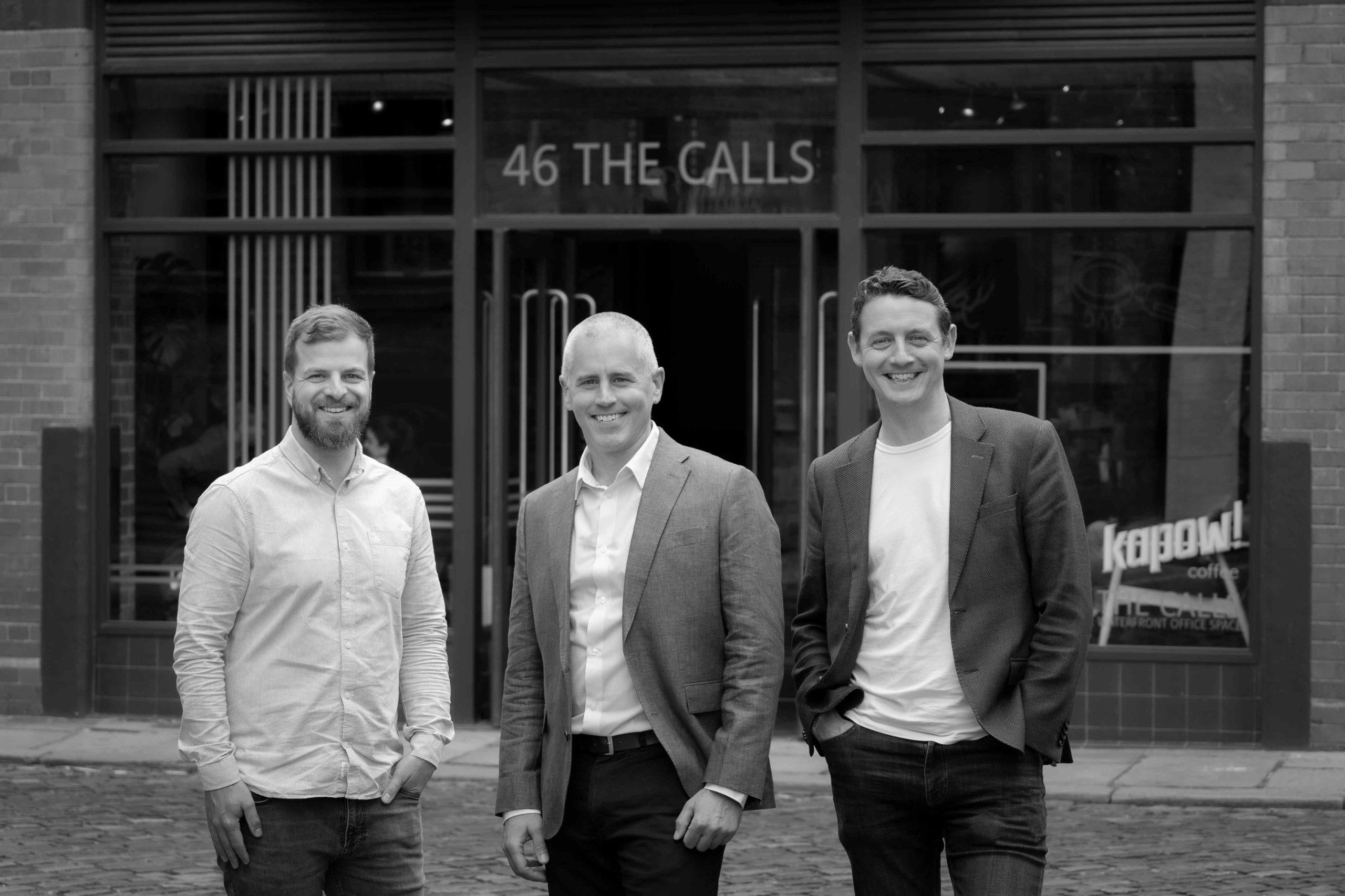 3 men stood infront of an office, black and white image